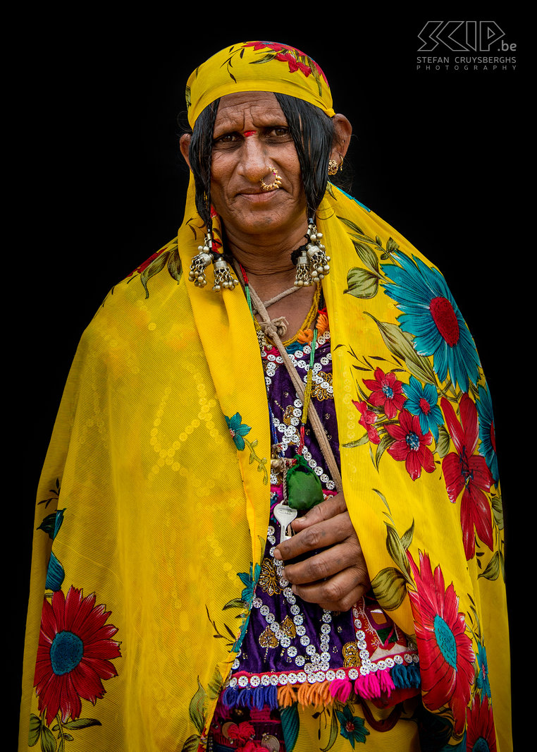Banjara vrouw De Banjara of Lambani zijn een nomadisch volk afkomstig uit de Indiase deelstaat Rajasthan, die nu verspreid over het Indische subcontinent leven. Zij zijn de grootste zigeuner-groep in India. In het verleden waren ze nomadisch en verhandelden en transporteerden ze zout, granen, brandhout en vee. Tegenwoordig hebben de meesten van hen een vaste woonplaats. De vrouwen maken kleurrijke geborduurde kleding met stukjes spiegel, decoratieve kralen en oude munten. Ze dragen ook sierlijke juwelen en sommige van hen hebben tatoeages. Banjara’s spreken Gor Boli, een taal die afkomstig is van het Sanskriet. Tegenwoordig spreken ze daarnaast ook de overheersende taal van hun omgeving. Ik fotografeerde een paar Banjara vrouwen op verschillende locaties in de deelstaat Karnataka in het zuiden van India. Stefan Cruysberghs